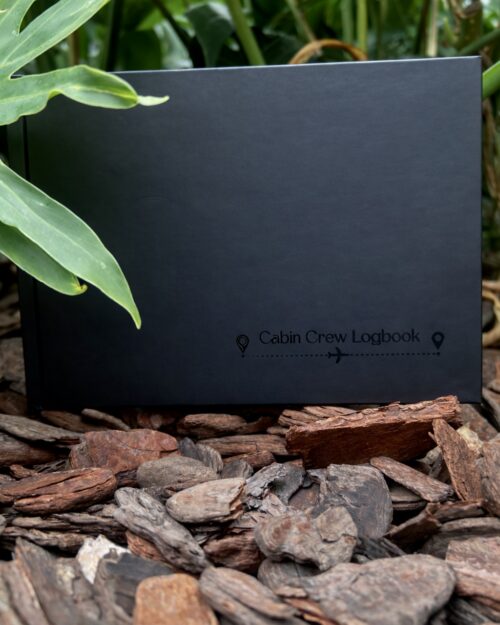Cabin crew logbook for flight attendants placed outdoors among natural greenery and stones, designed for tracking flights, training and aviation career progress